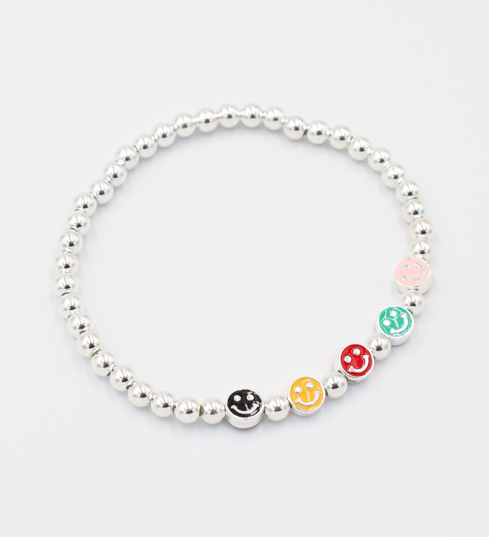 Side view of adjustable sterling silver bracelet with five colorful smiley face beads and silver beads.