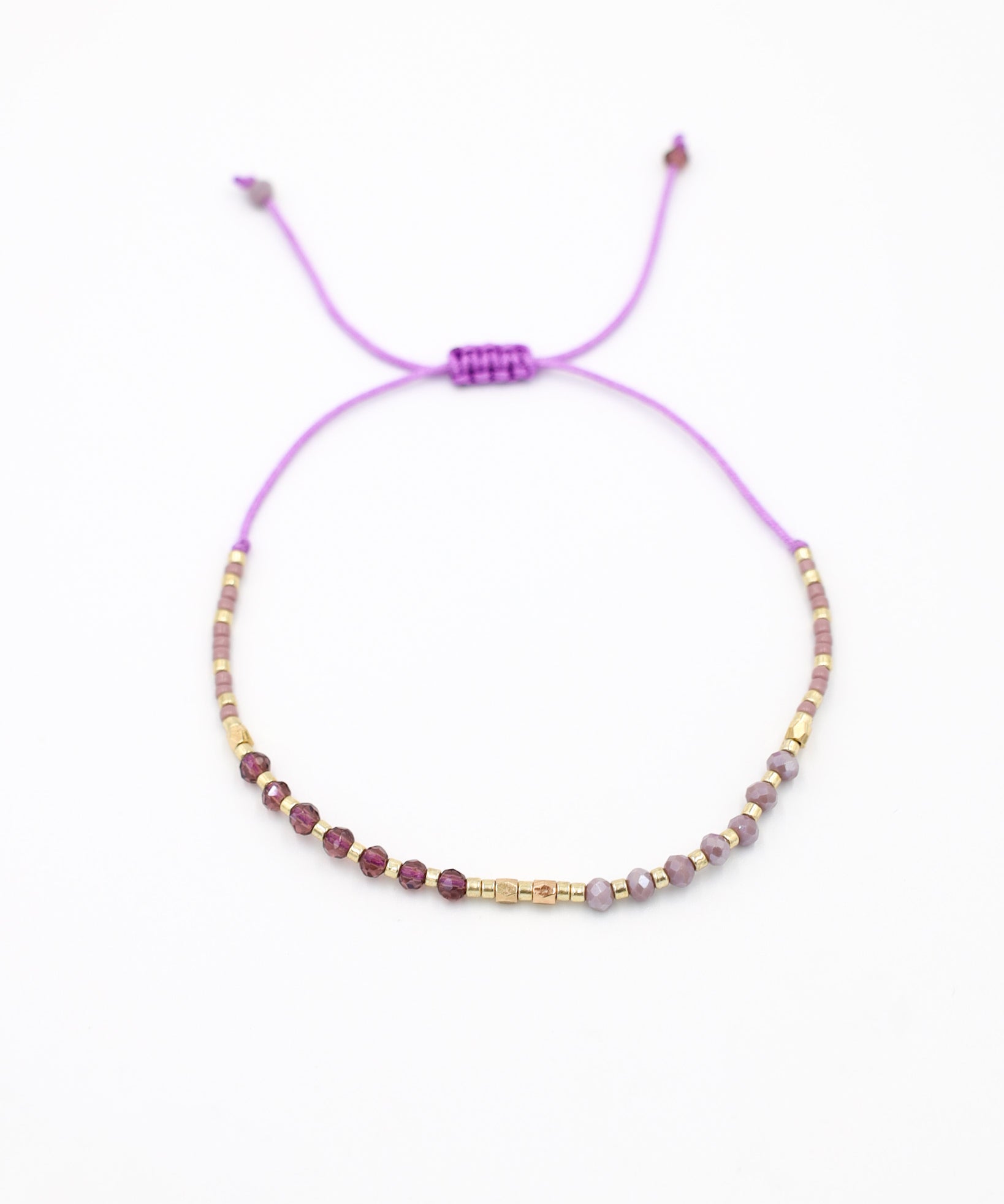 An adjustable gold-colored bracelet with a series of round beads and rhinestone accents, featuring a purple clasp.