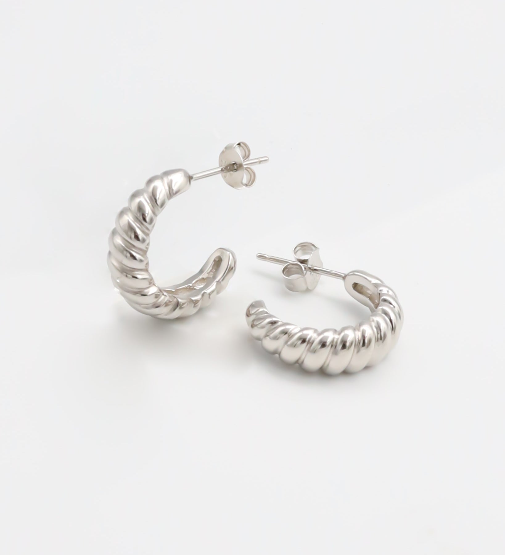 A pair of silver hoop earrings on a white background