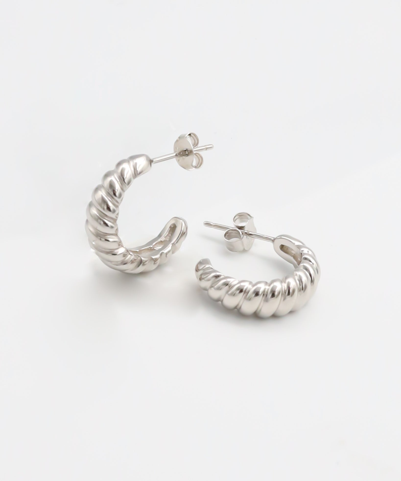 A pair of silver hoop earrings on a white background