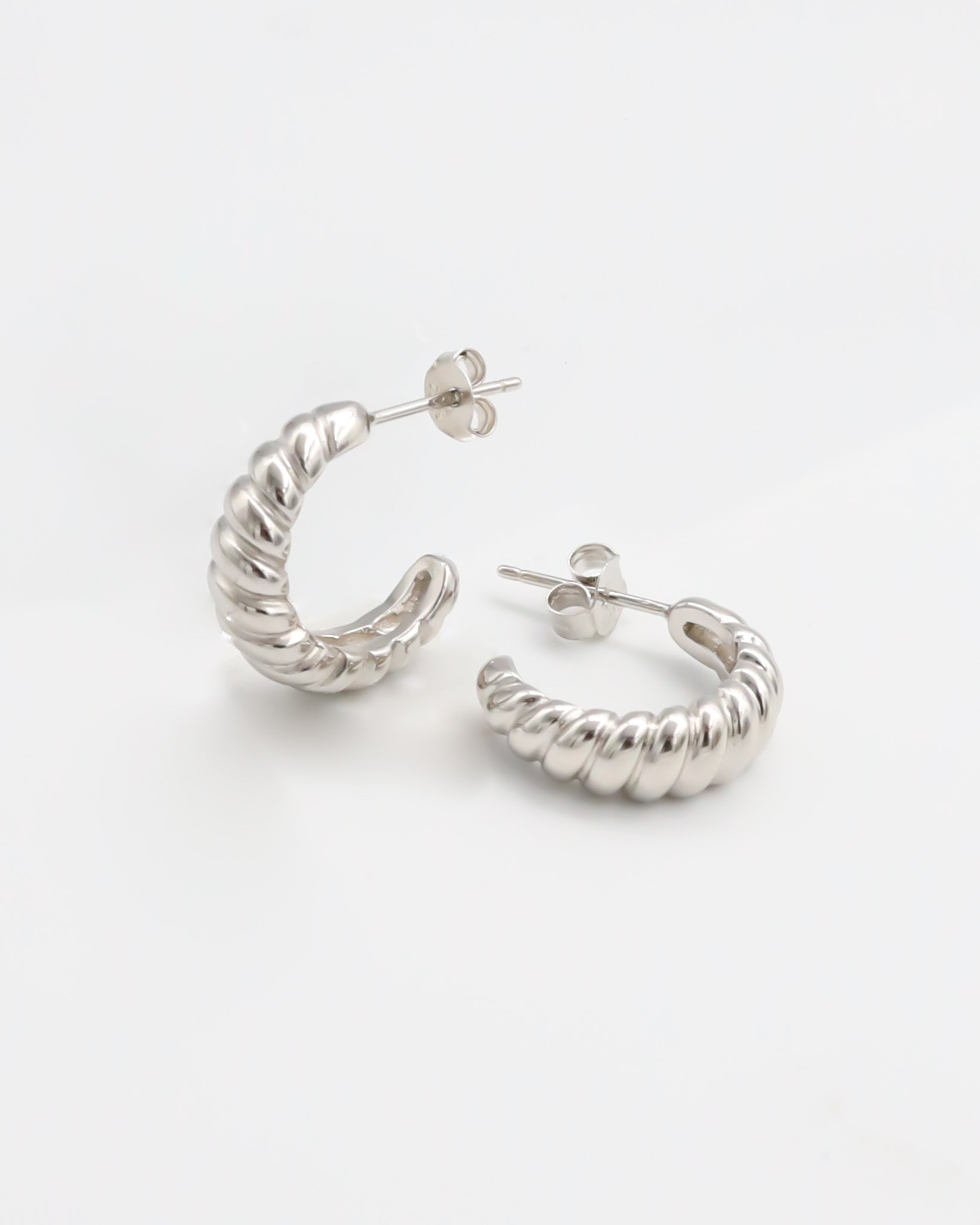 A pair of silver hoop earrings on a white background