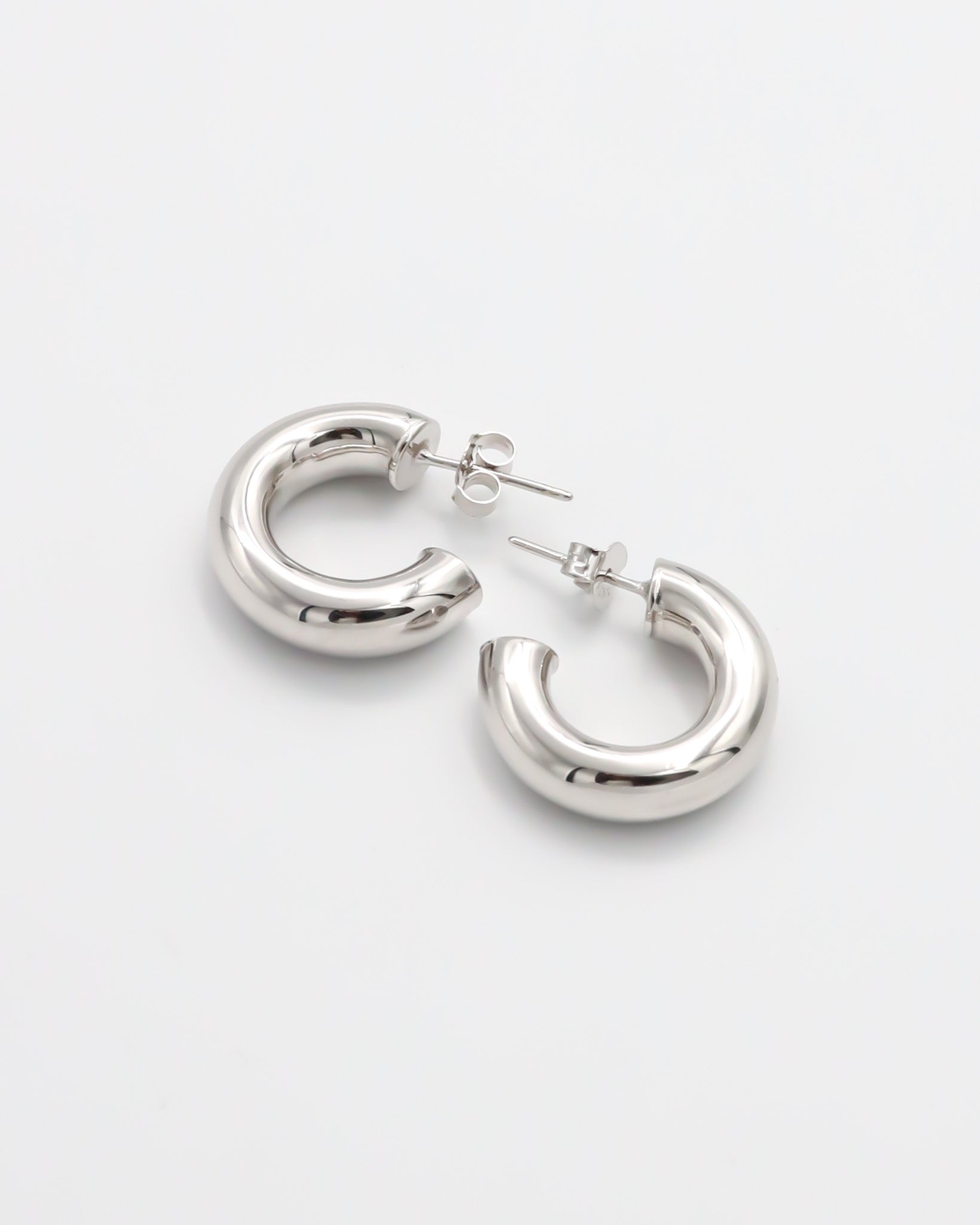 A pair of silver hoop earrings with a pressure system anchoring, displayed against a white background.
