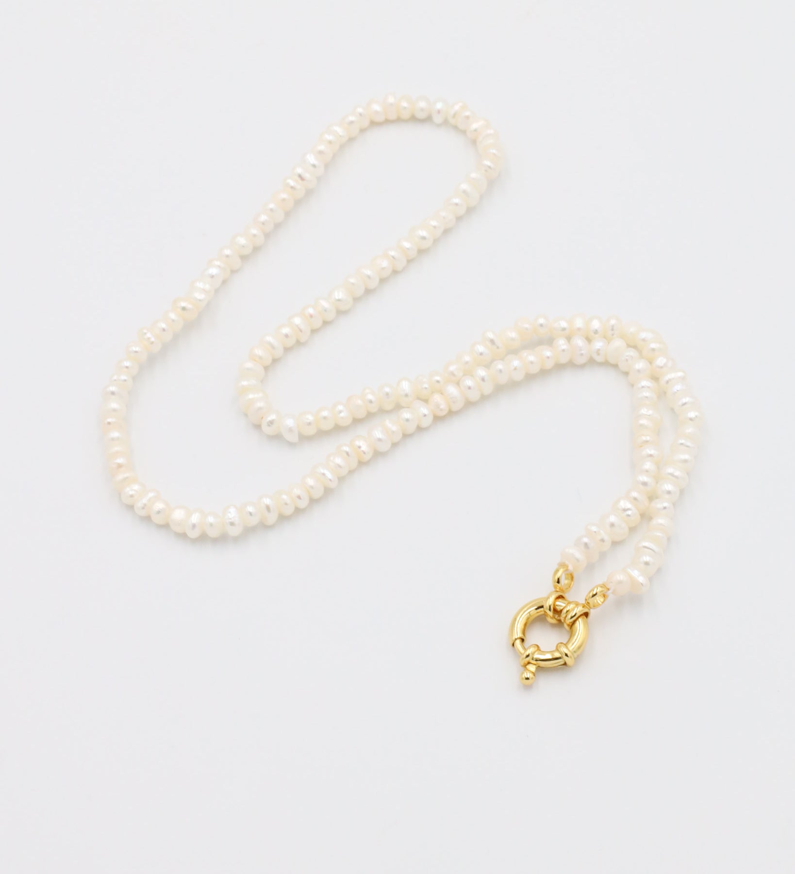 A white pearl necklace with a gold clasp on a white background.