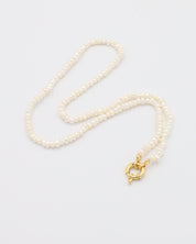 A white pearl necklace with a gold clasp on a white background.