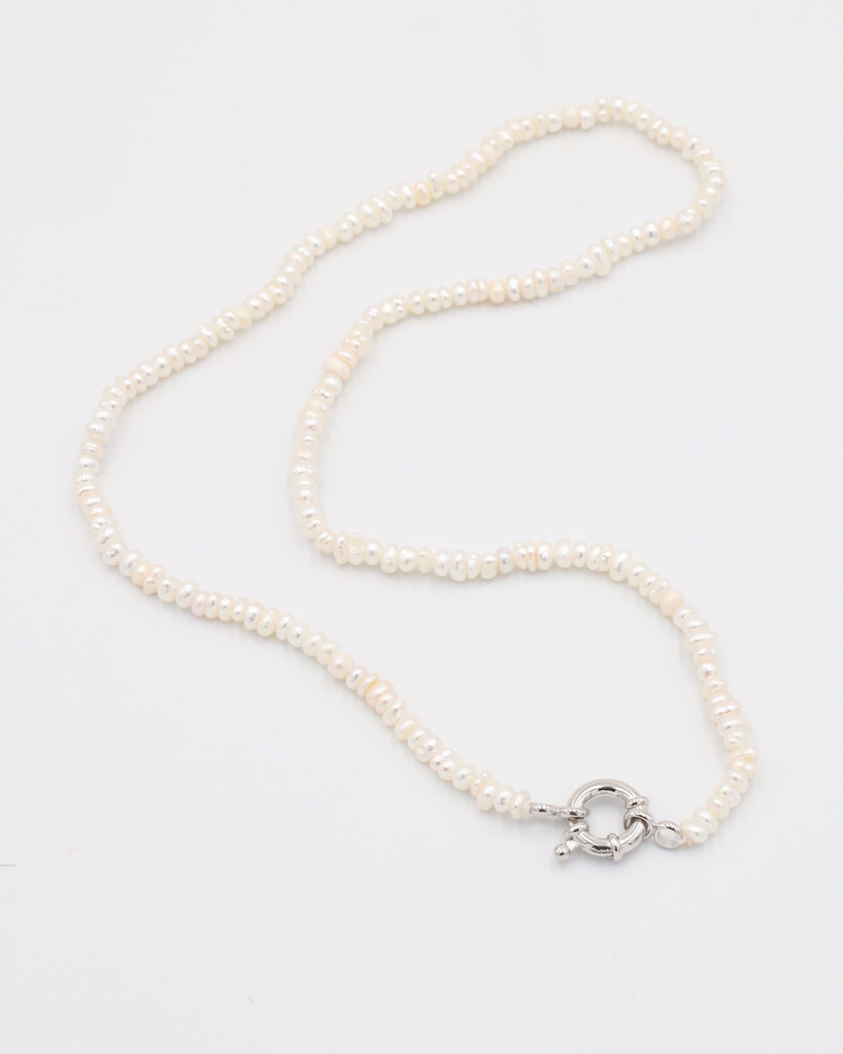A silver-colored necklace with a pearl-like texture and a metallic clasp, displayed against a white background.