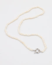 A silver-colored necklace with a pearl-like texture and a metallic clasp, displayed against a white background.