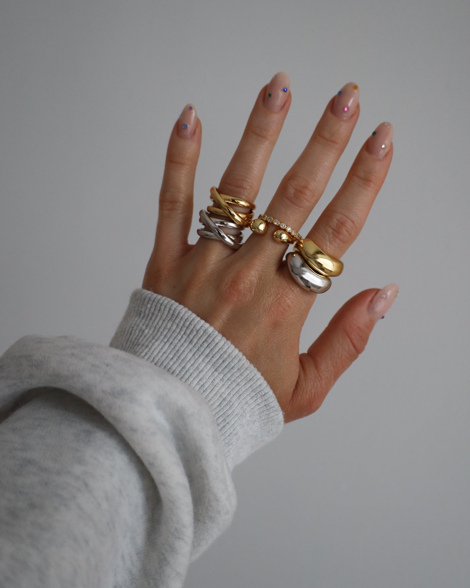 A gold-colored ring with multiple gemstones set around its circumference worn on a hand. 
