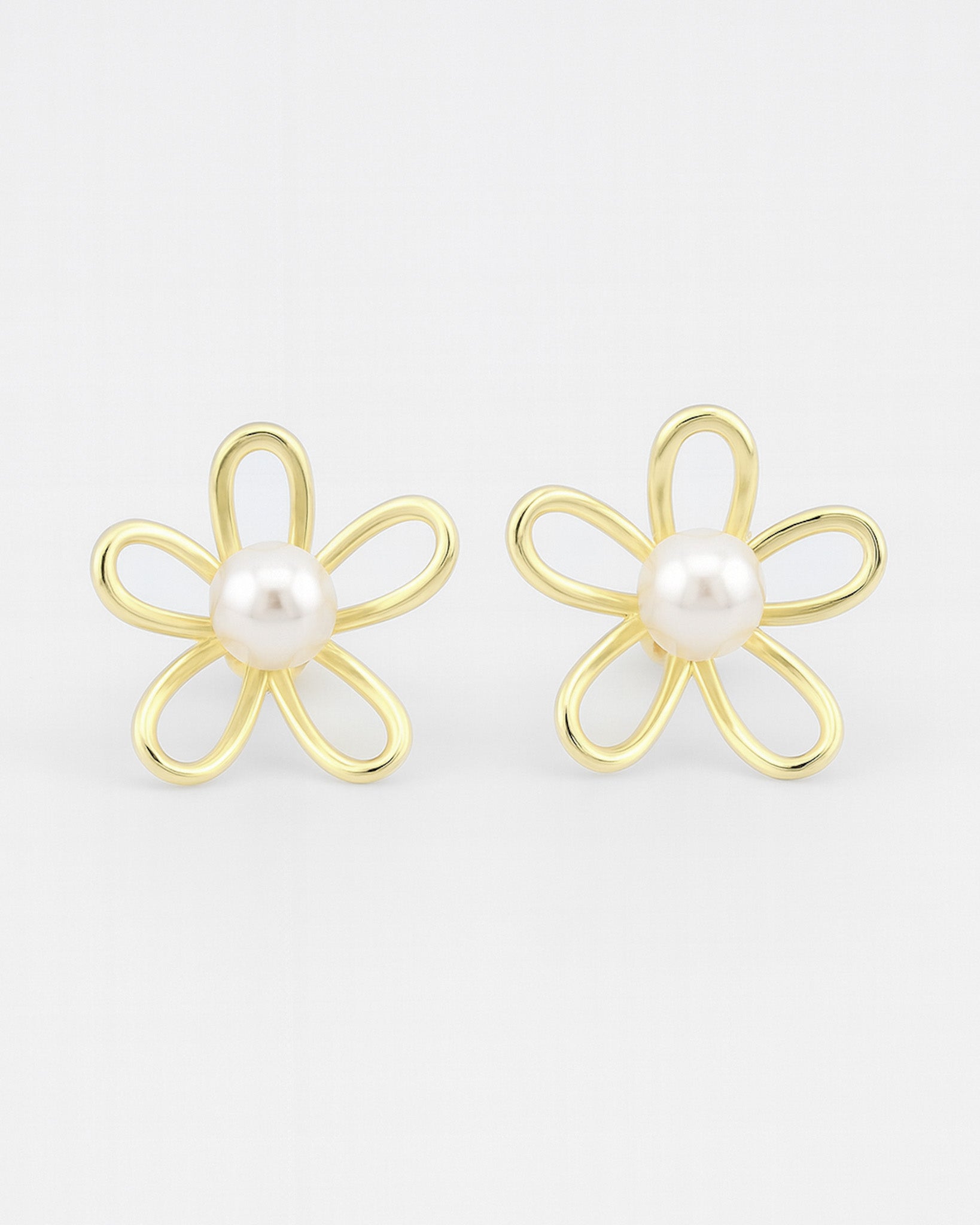 Gold flower-shaped earrings with pearl centers on a white background