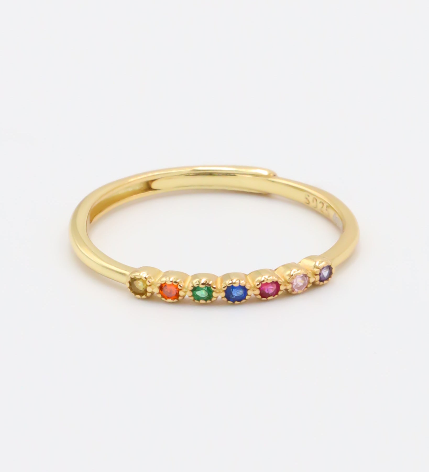 A gold-colored ring with multiple multicolored gemstones set close together.