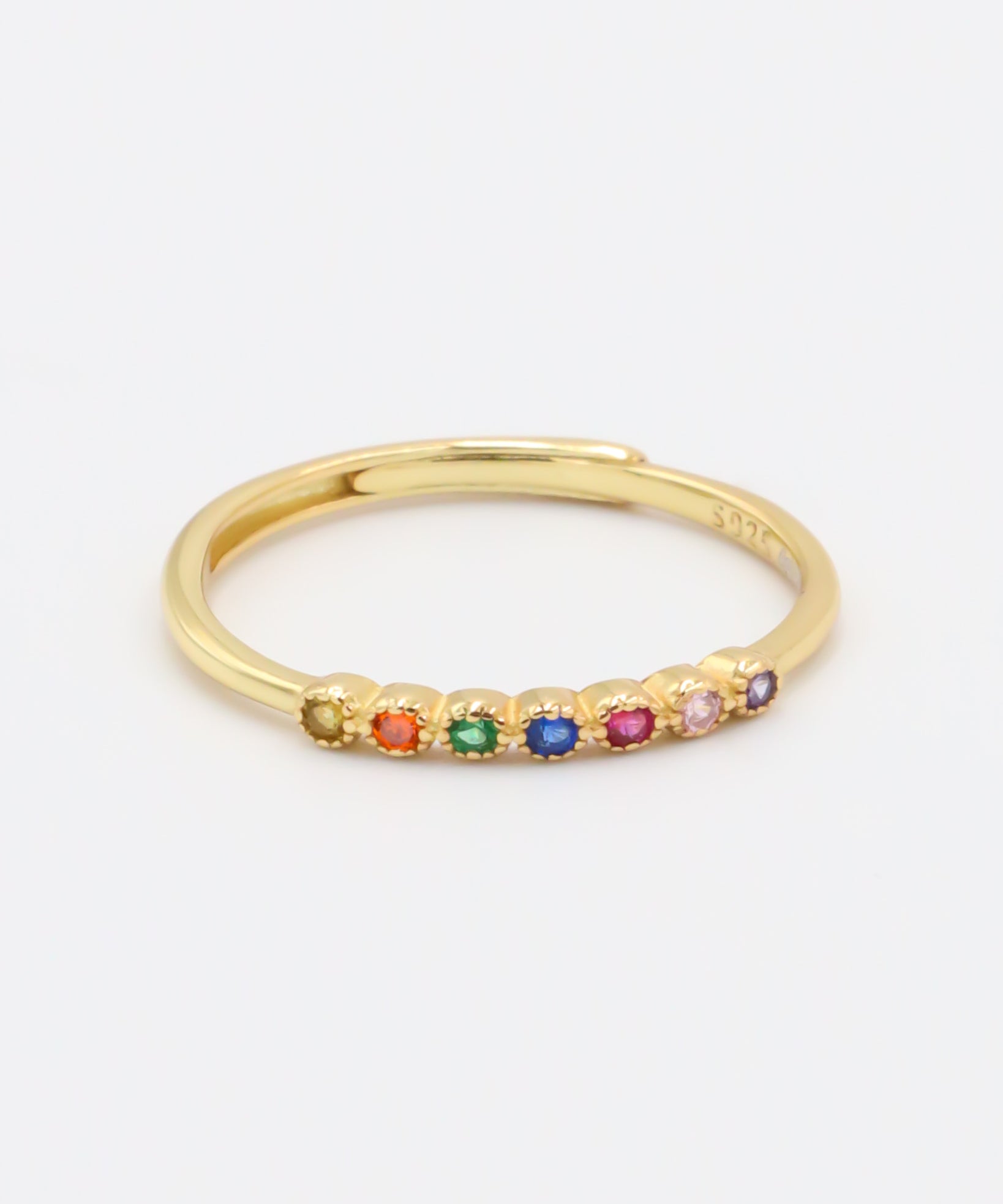 A gold-colored ring with multiple multicolored gemstones set close together.