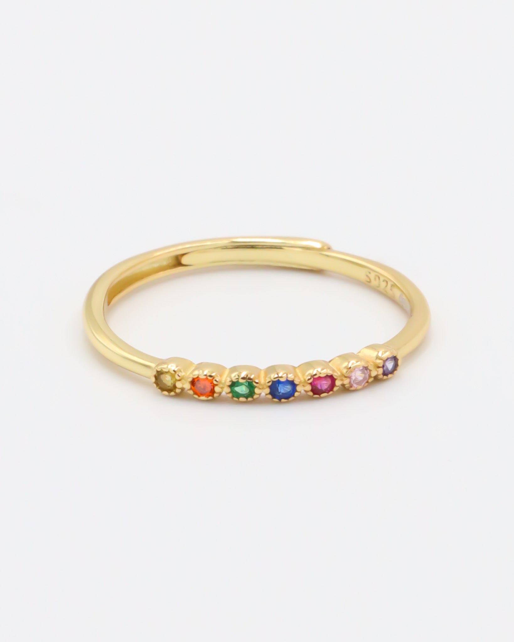 A gold-colored ring with multiple multicolored gemstones set close together.
