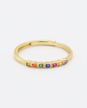 A gold-colored ring with multiple multicolored gemstones set close together.