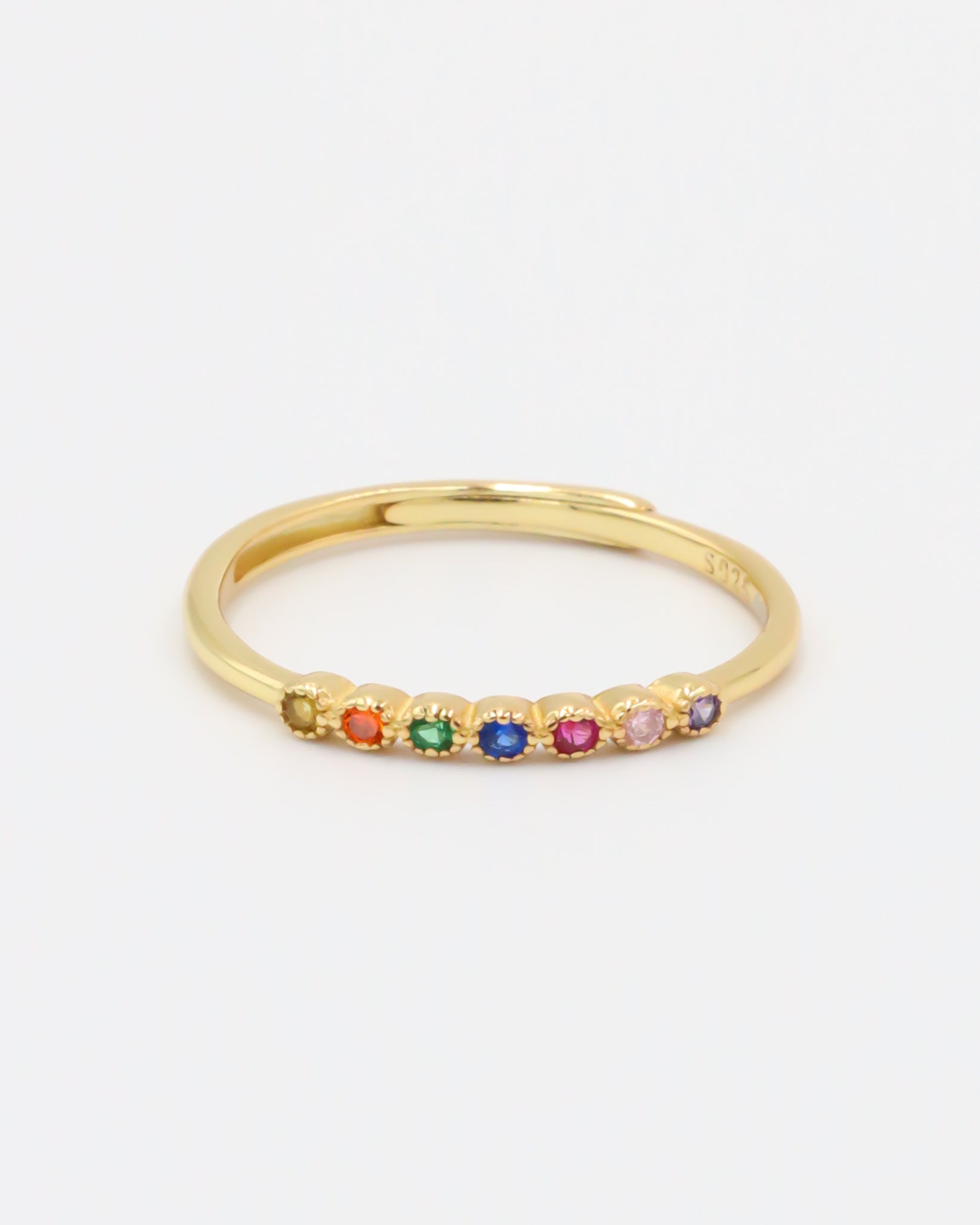 A gold-colored ring with multiple multicolored gemstones set close together.