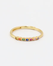 A gold-colored ring with multiple multicolored gemstones set close together.