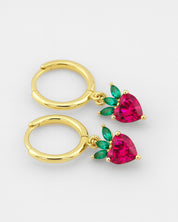 Gold hoop earrings with heart-shaped red gemstones and green leaves on a white background