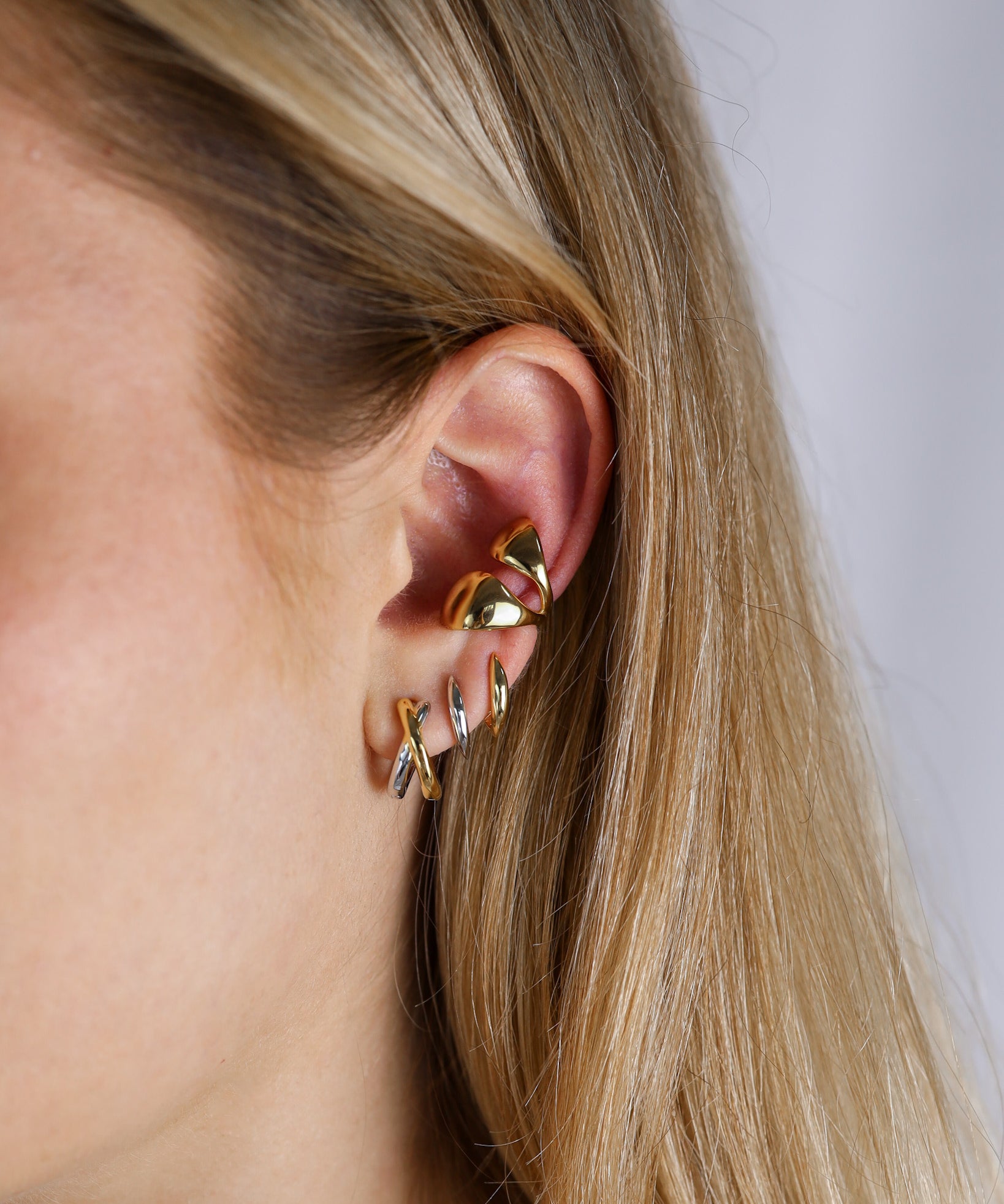 Rebel earring worn by a person with blonde hair on a neutral background, matched with Samantha hoops and ear cuff