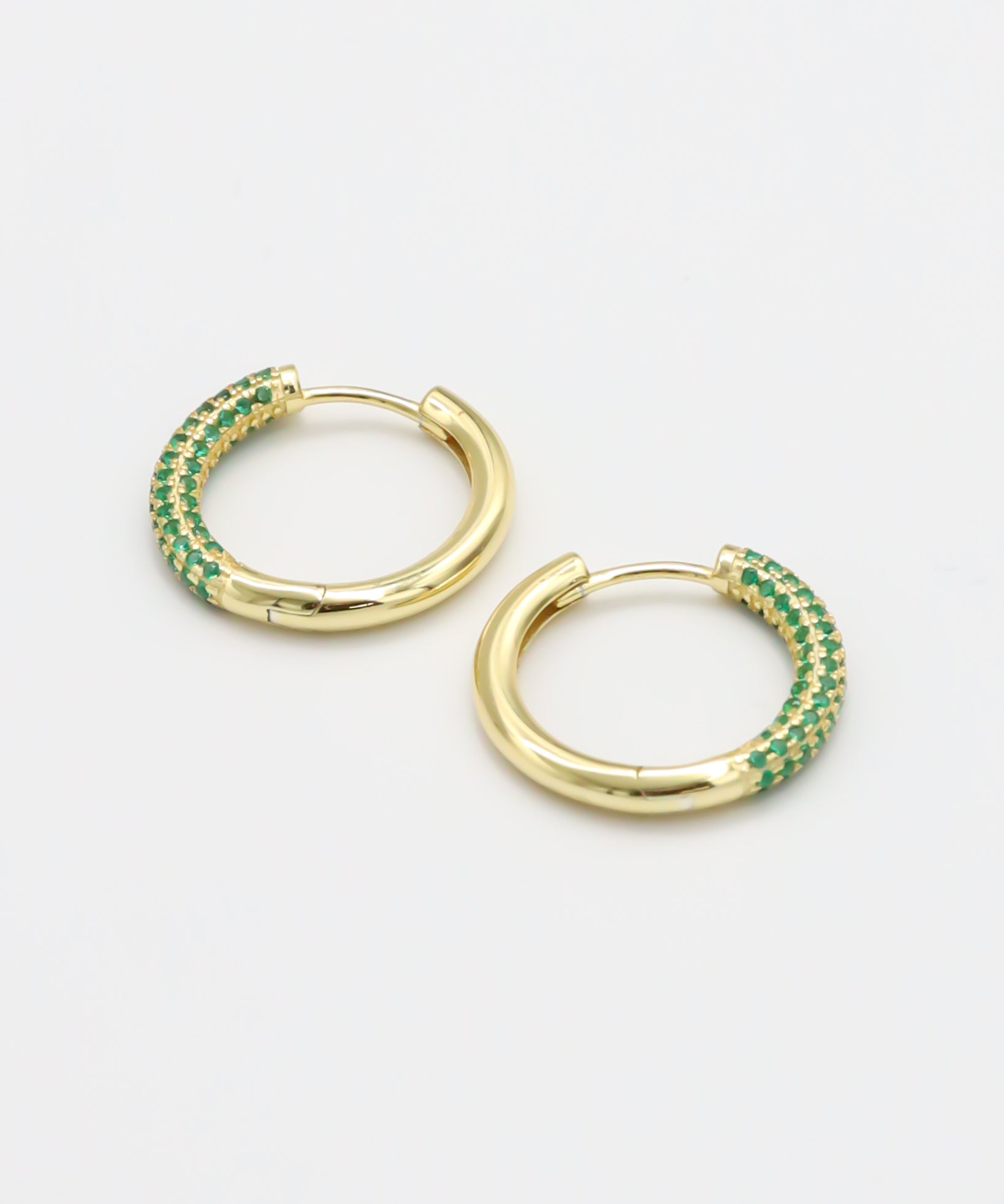 A pair of gold-colored hoop earrings with green accents, displayed against a white background.