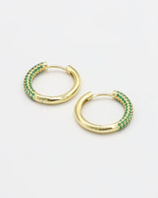 A pair of gold-colored hoop earrings with green accents, displayed against a white background.