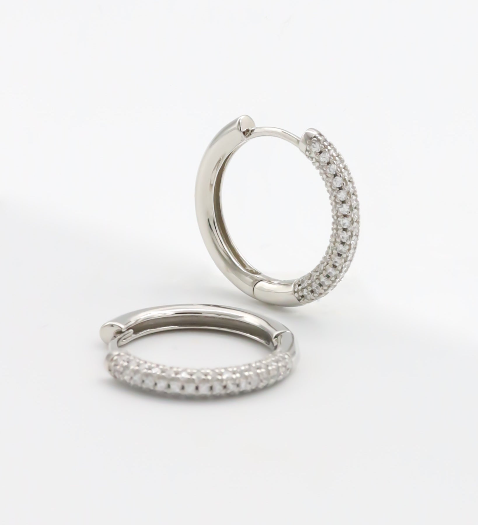 A pair of silver-colored hoop earrings with a pressure system anchoring, displayed against a white background.