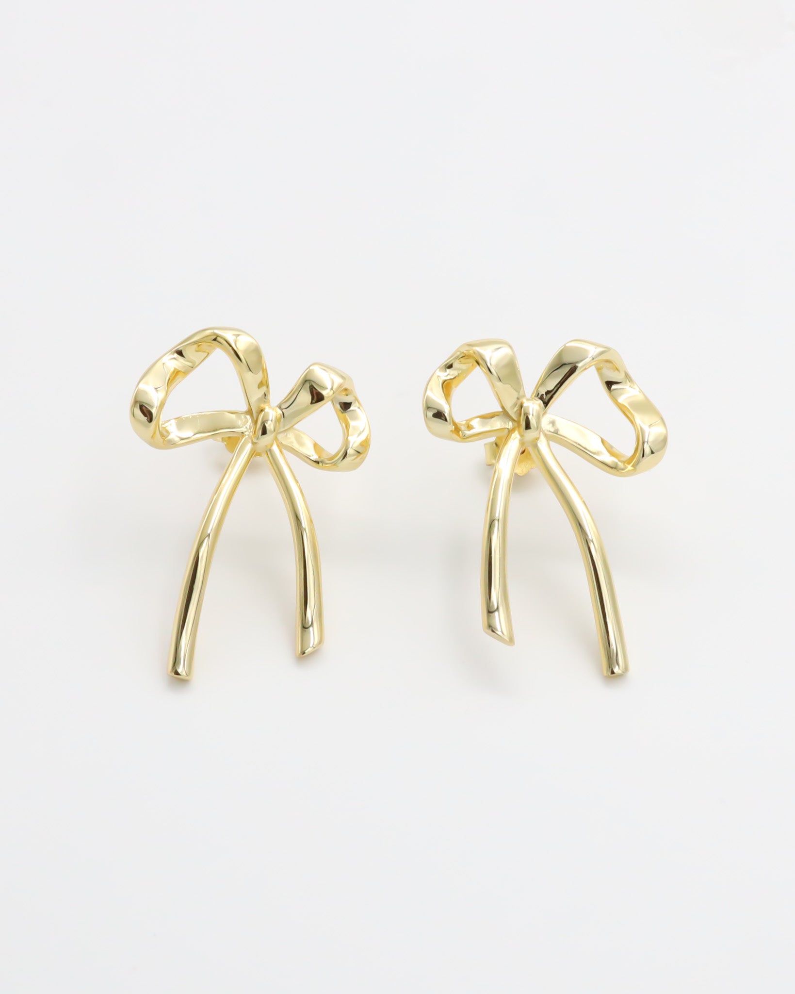 A pair of gold bow-shaped earrings on a white background