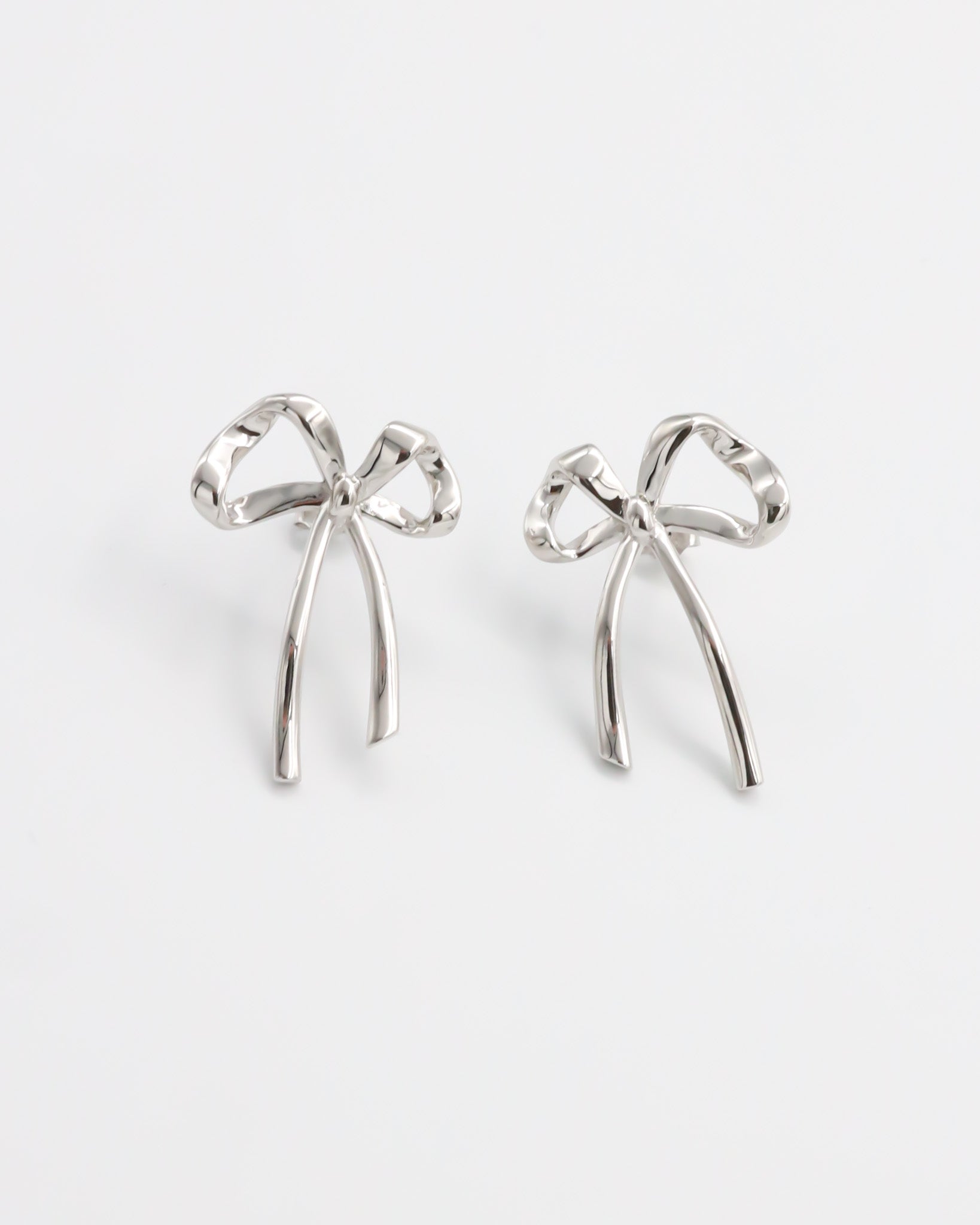 A pair of silver bow-shaped earrings on a white background