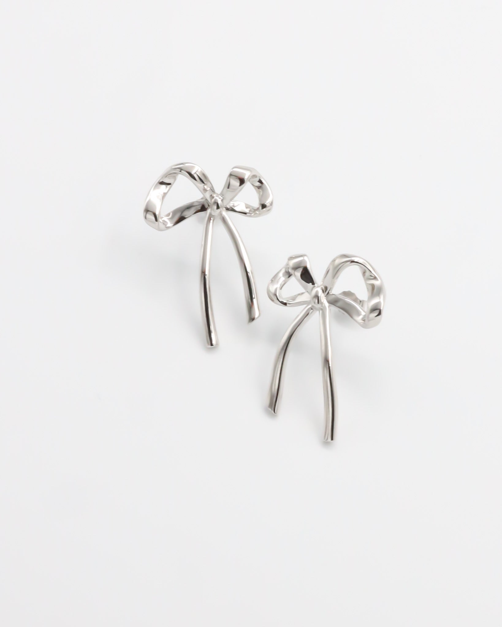 A pair of silver bow-shaped earrings on a white background