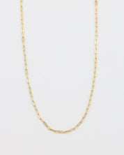 A gold-colored necklace with a chain link design, laid out on a plain background.