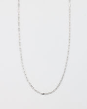 A silver necklace with a chain link design, laid out on a plain background.