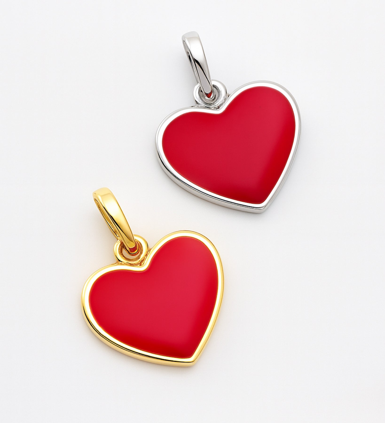Two heart-shaped pendants, one gold and one silver, on a light gray background.