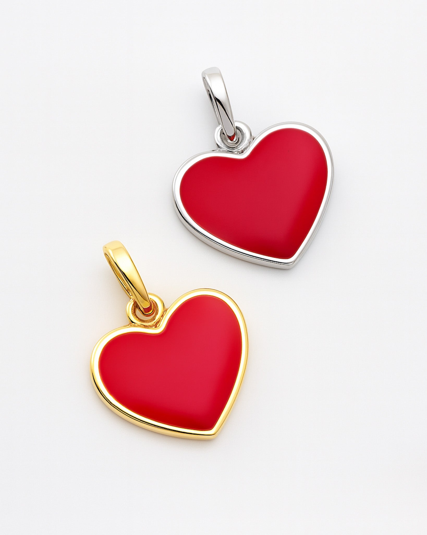 Two heart-shaped pendants, one gold and one silver, on a light gray background.
