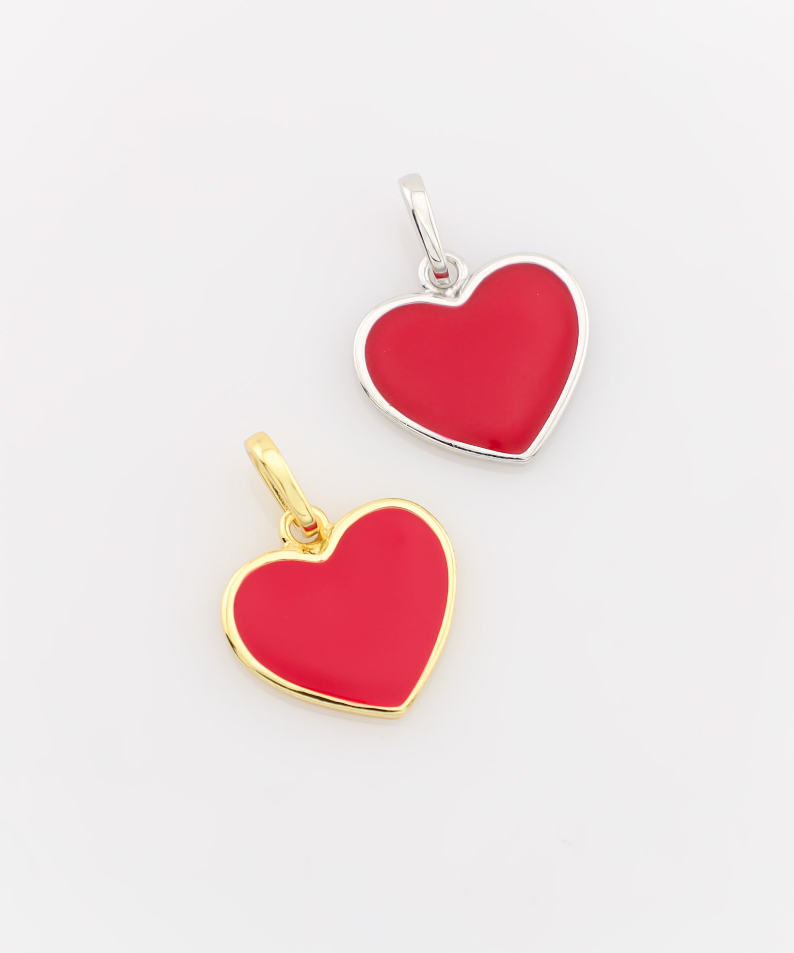 Two heart-shaped pendants, one gold and one silver, on a light gray background.