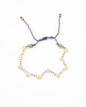 Beaded bracelet in gray, white and gold tones with a zigzag pattern and adjustable sliding closure, laid flat on a white background.