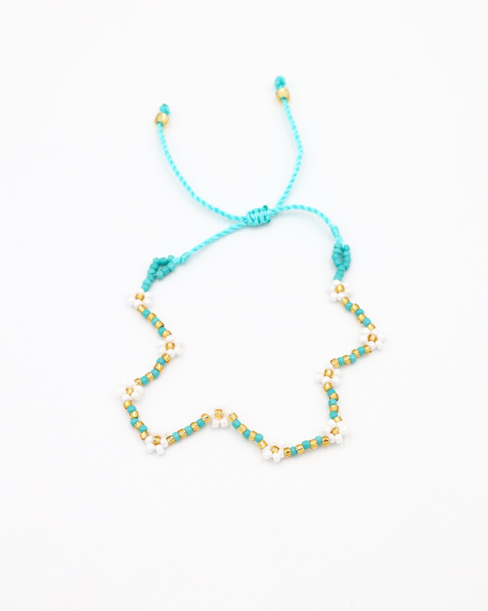 Beaded bracelet in blue, white and gold tones with a zigzag pattern and adjustable sliding closure, laid flat on a white background.