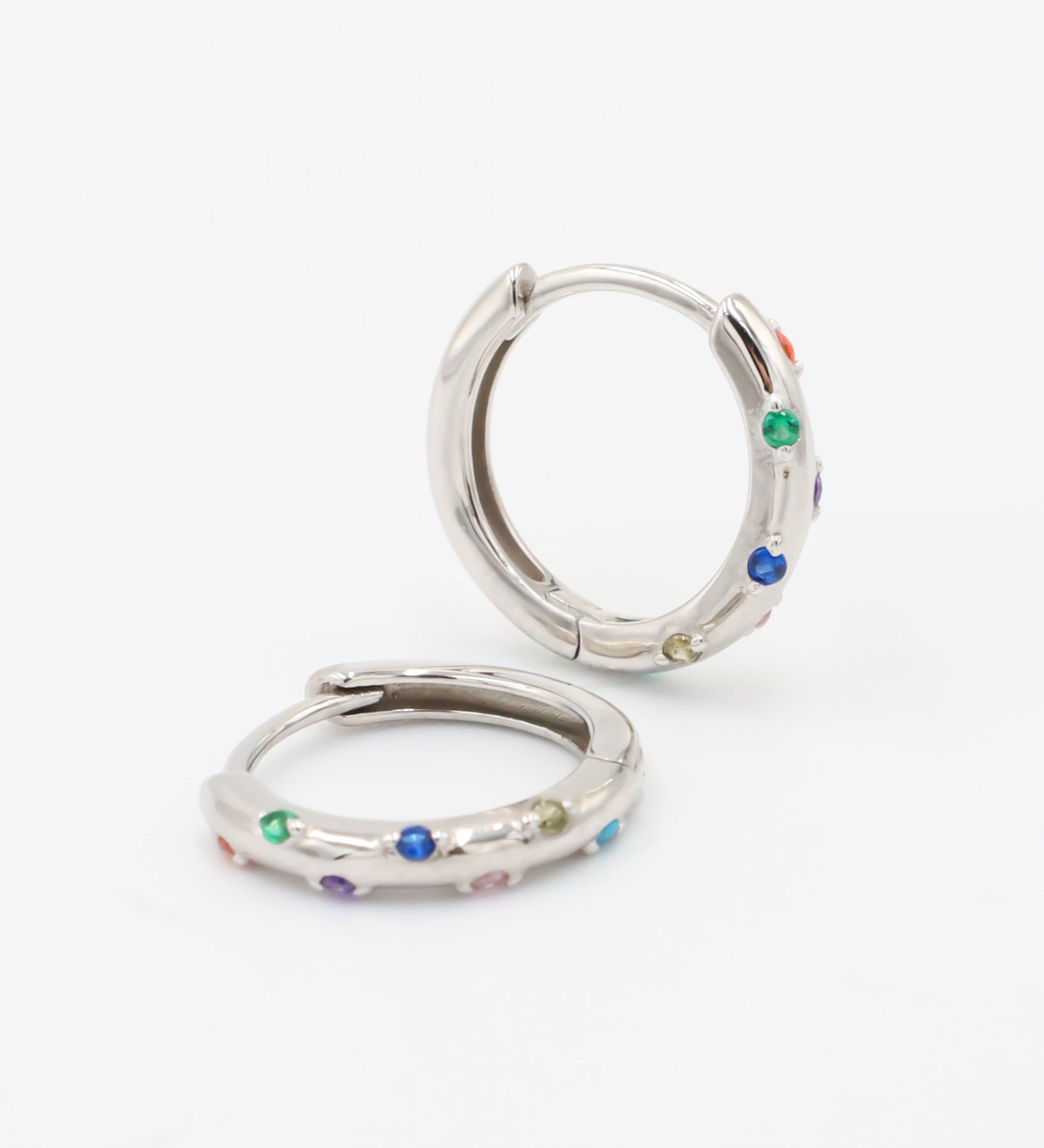A pair of silver-colored hoop earrings with multicolored accents, displayed against a white background.