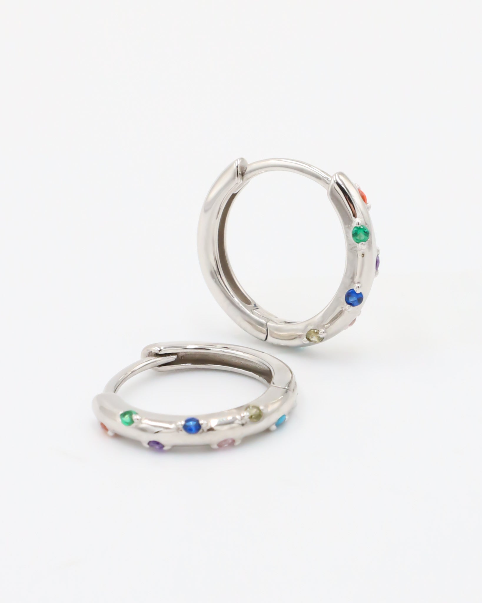 A pair of silver-colored hoop earrings with multicolored accents, displayed against a white background.