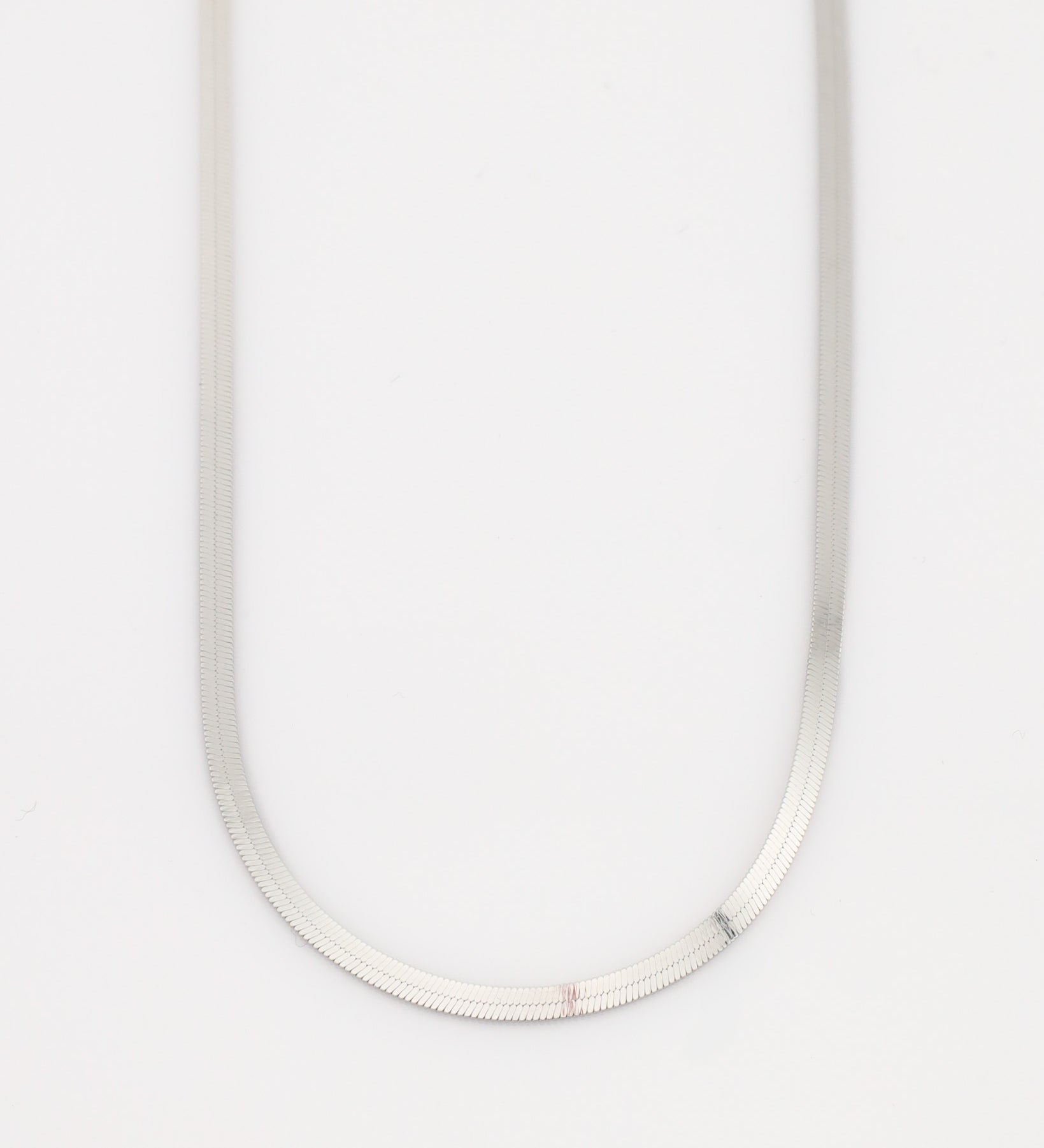 Silver necklace on a light gray background