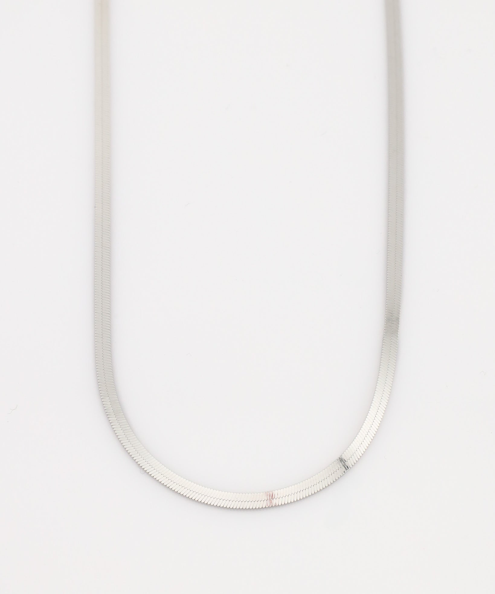 Silver necklace on a light gray background