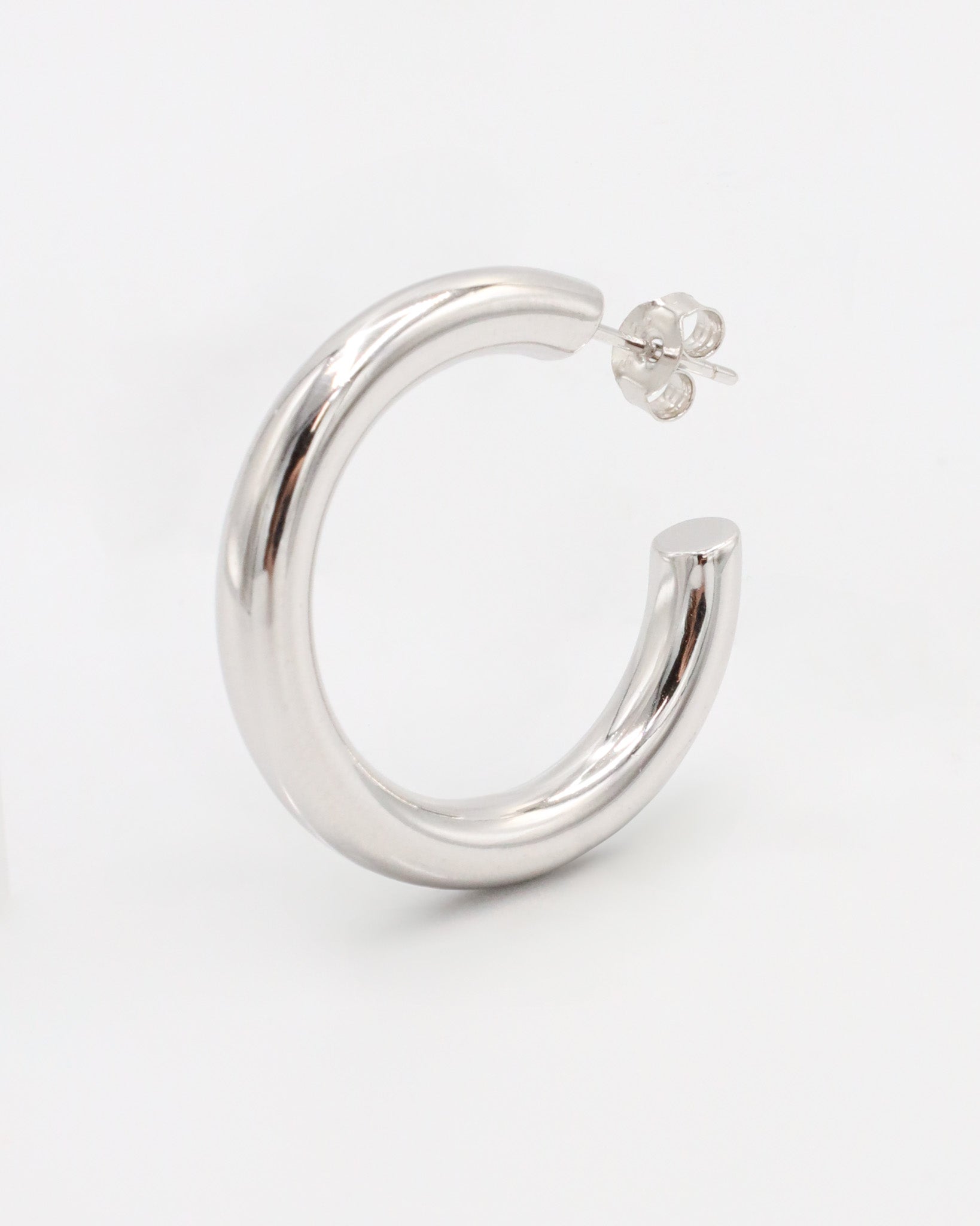 A pair of silver hoop earrings with a visible stud attachment, displayed against a white background.