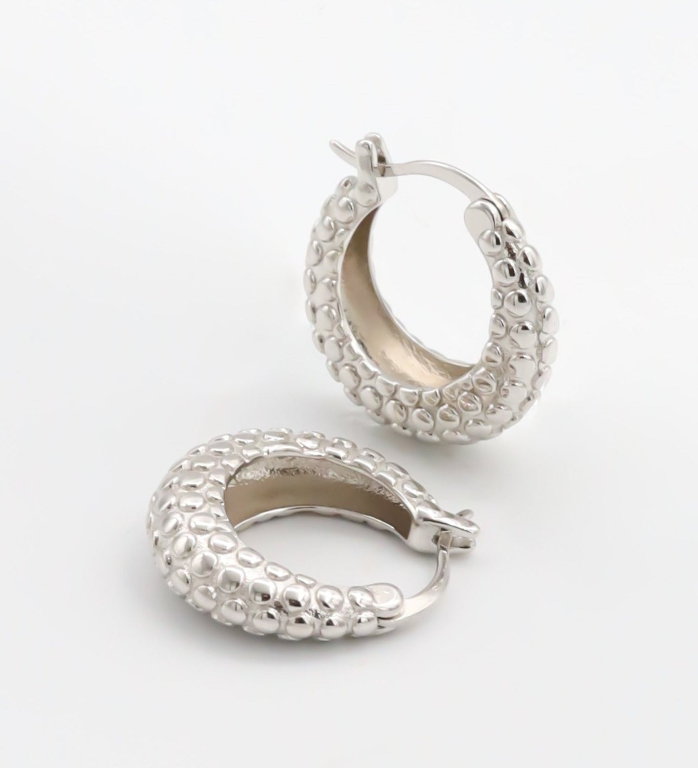 A pair of silver hoop earrings with a textured design, displayed against a white background.