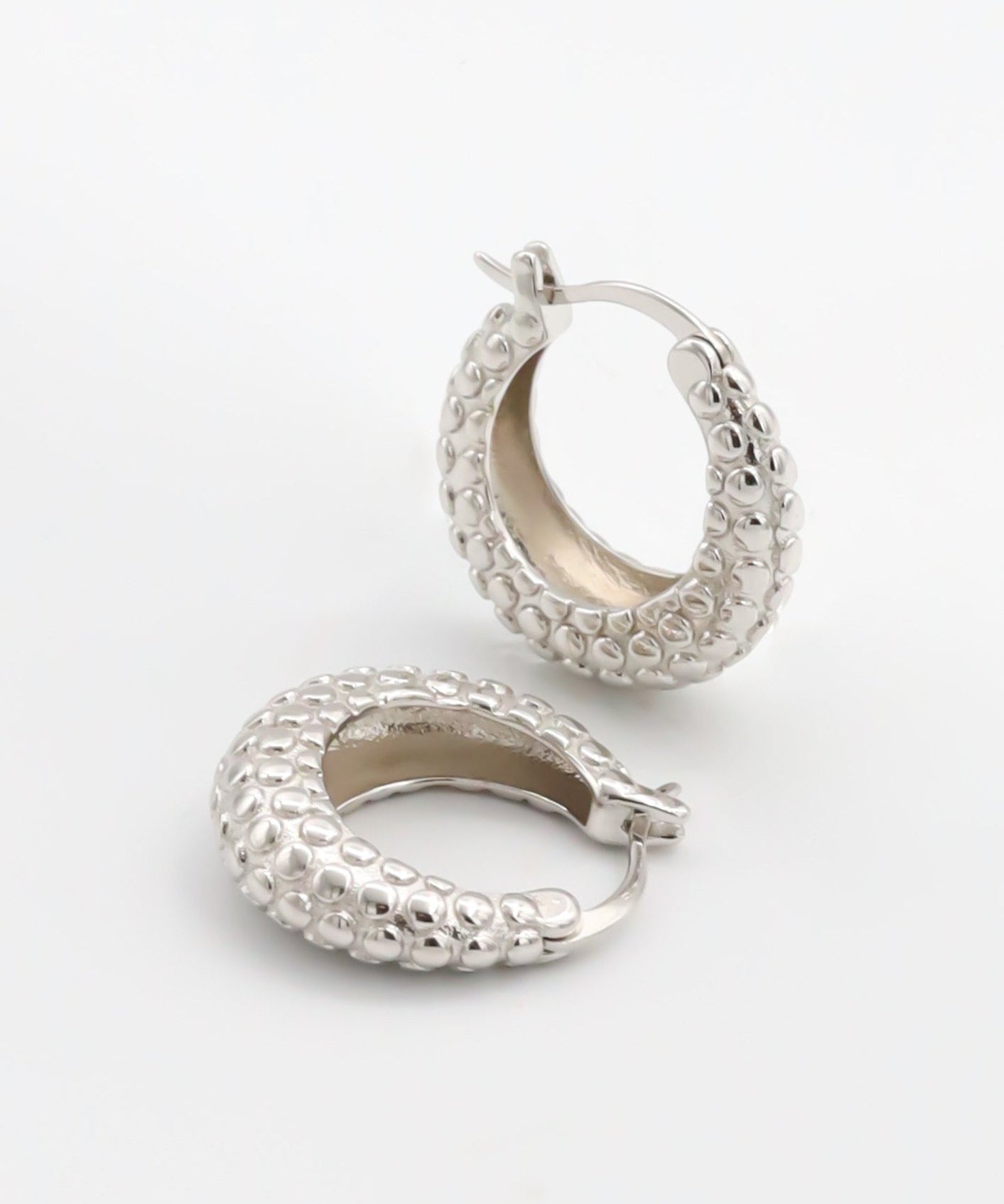 A pair of silver hoop earrings with a textured design, displayed against a white background.