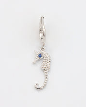 A close-up of a single silver hoop earring with a seahorse charm and a blue stone eye, displayed on a white background (Left Ear).
