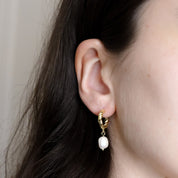 Close-up of a person wearing the Selina earring in gold on the lobe