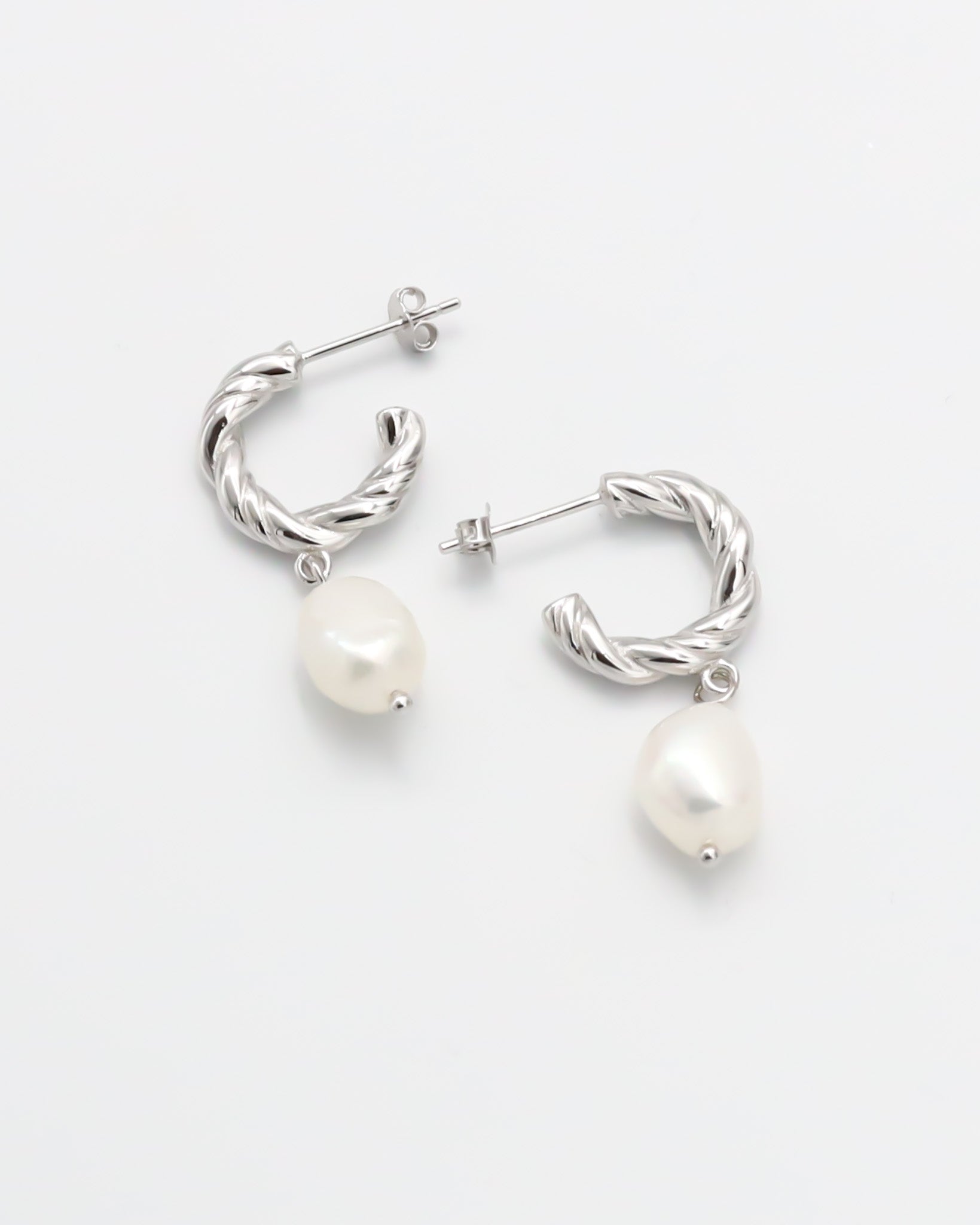 A pair of silver hoop earrings with white pearl studs.