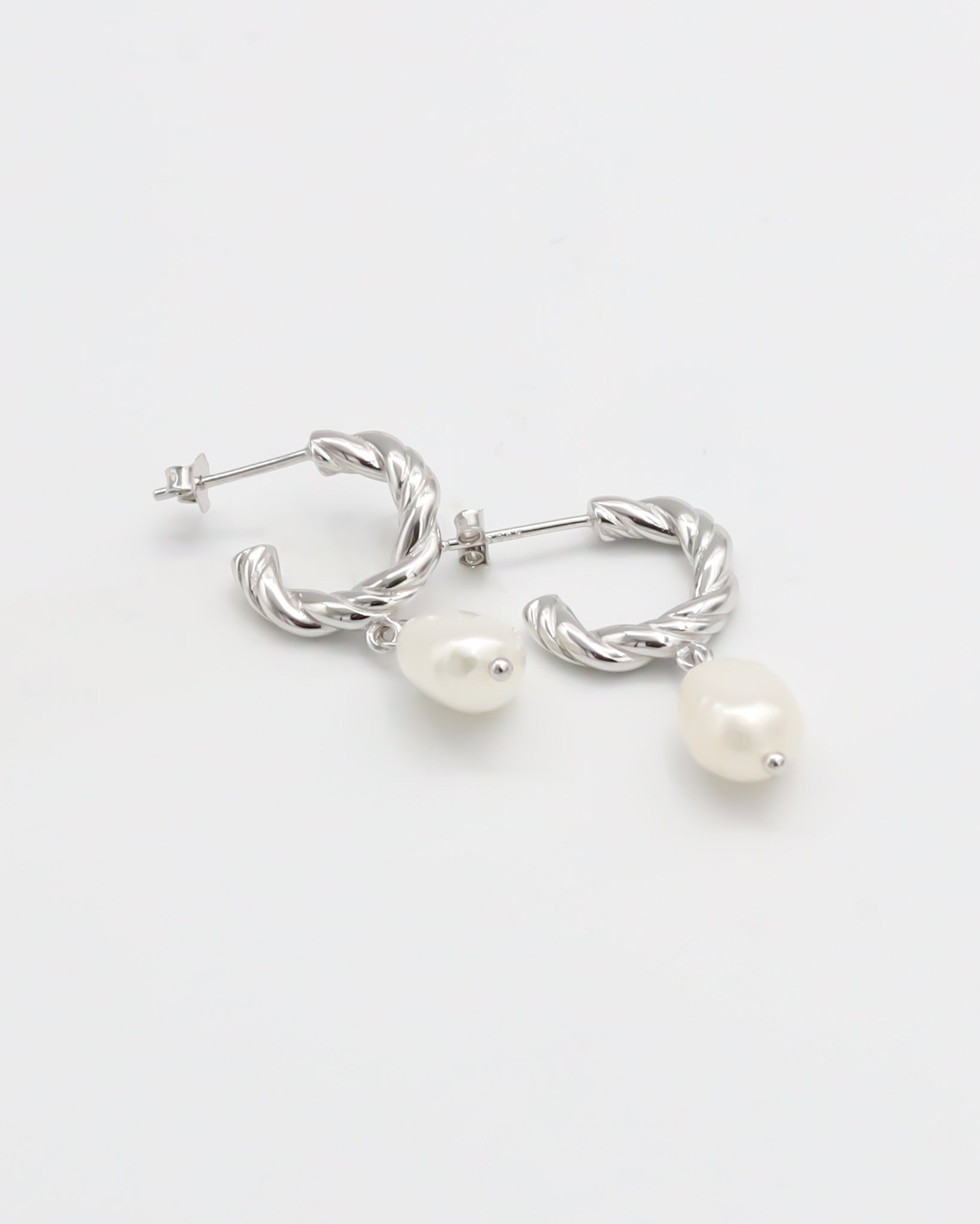 A pair of silver hoop earrings with white pearl studs.