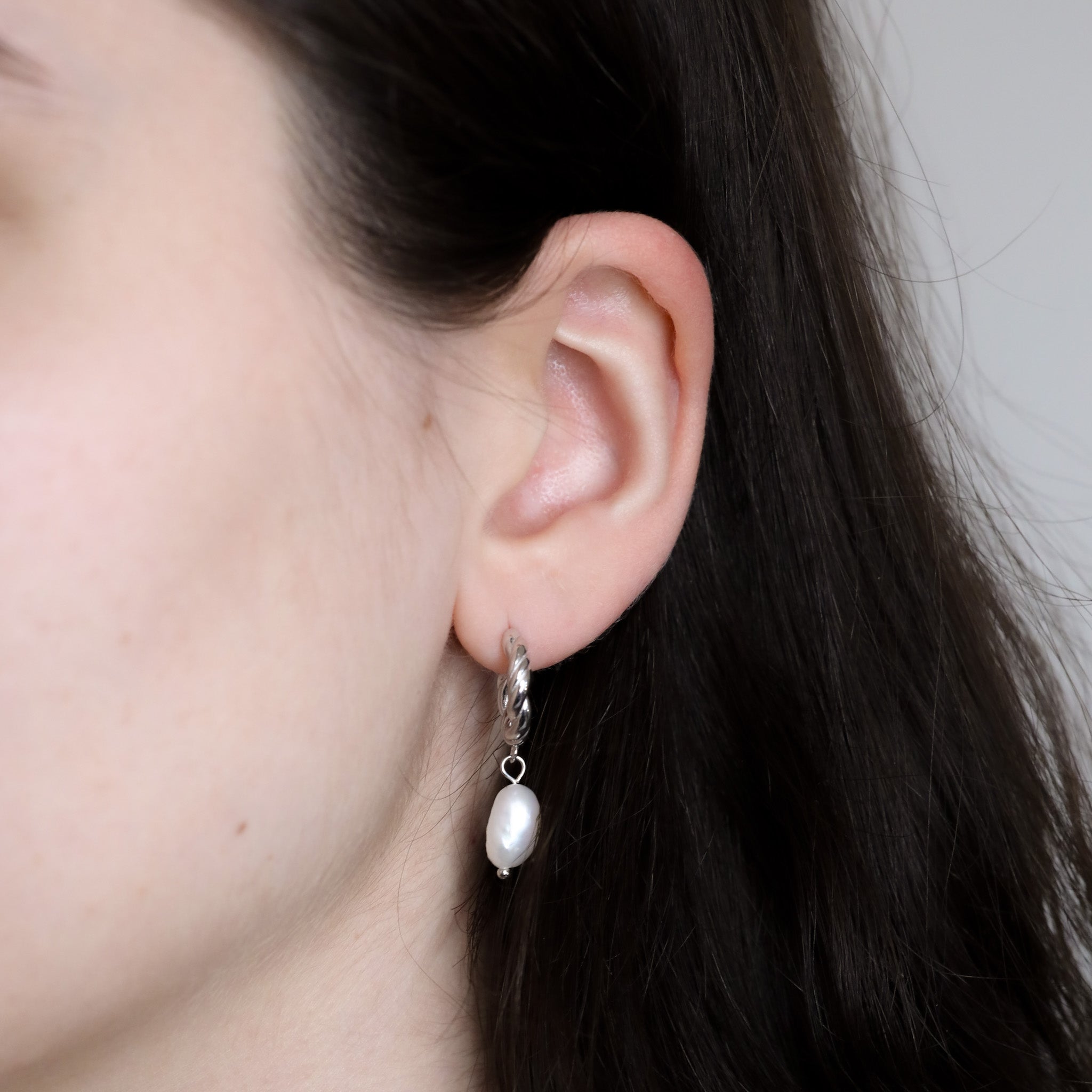 Close-up of a person wearing the Selina earring in silver on the lobe