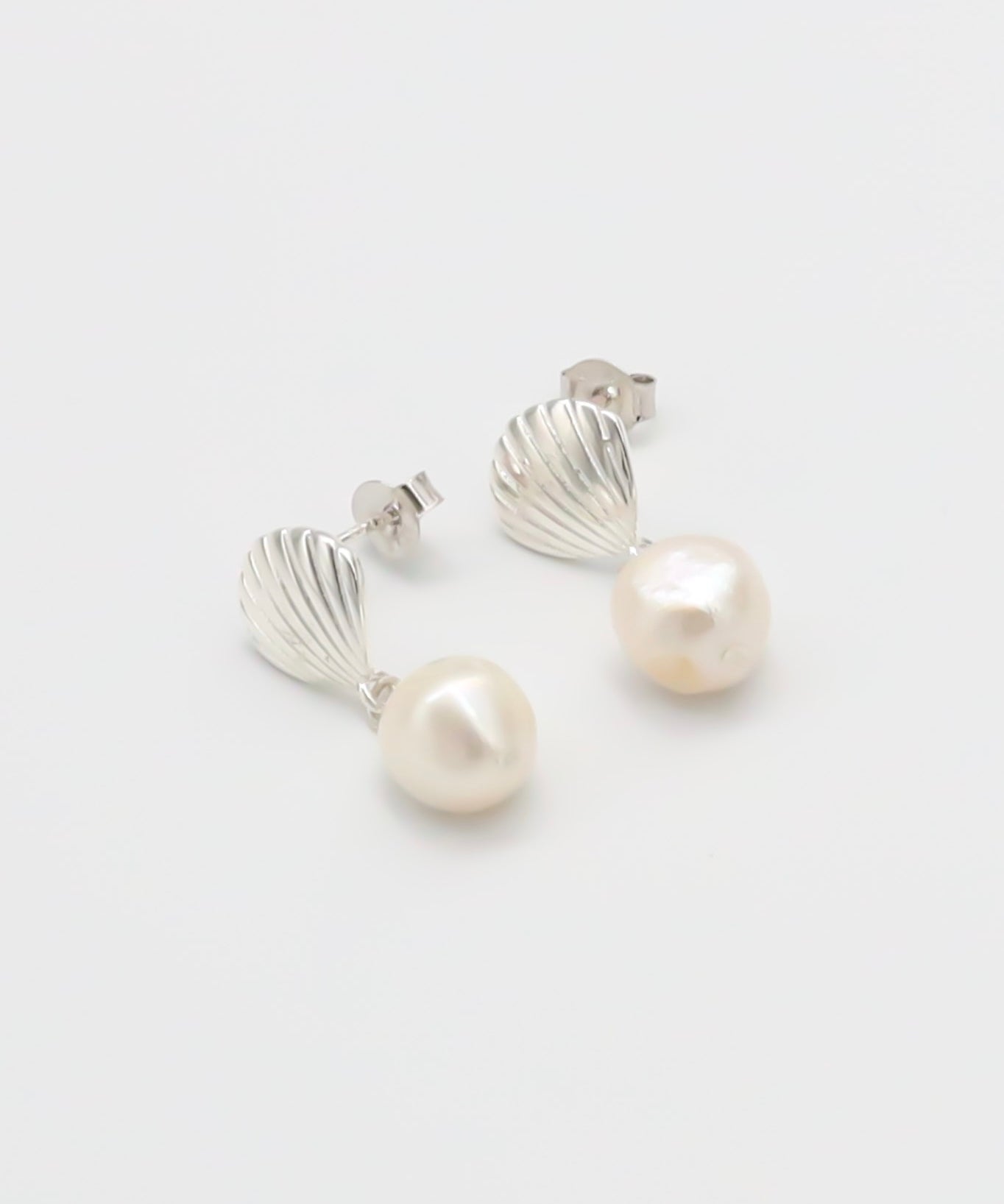 A pair of silver hoop earrings with white pearl accents on a white background.