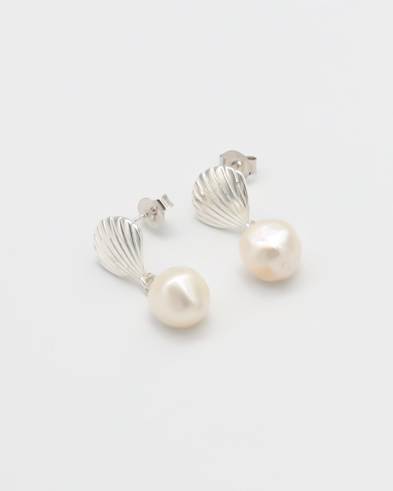 A pair of silver hoop earrings with white pearl accents on a white background.