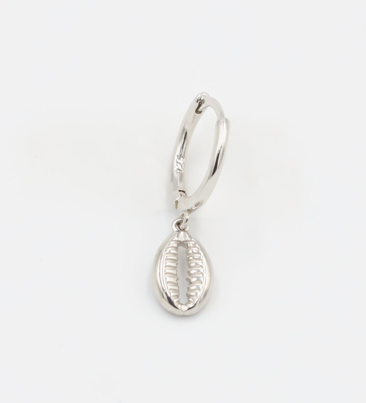A single silver hoop earring with a small dangling silver charm on a white background