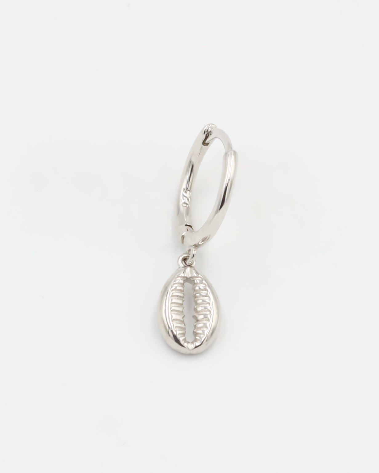 A single silver hoop earring with a small dangling silver charm on a white background