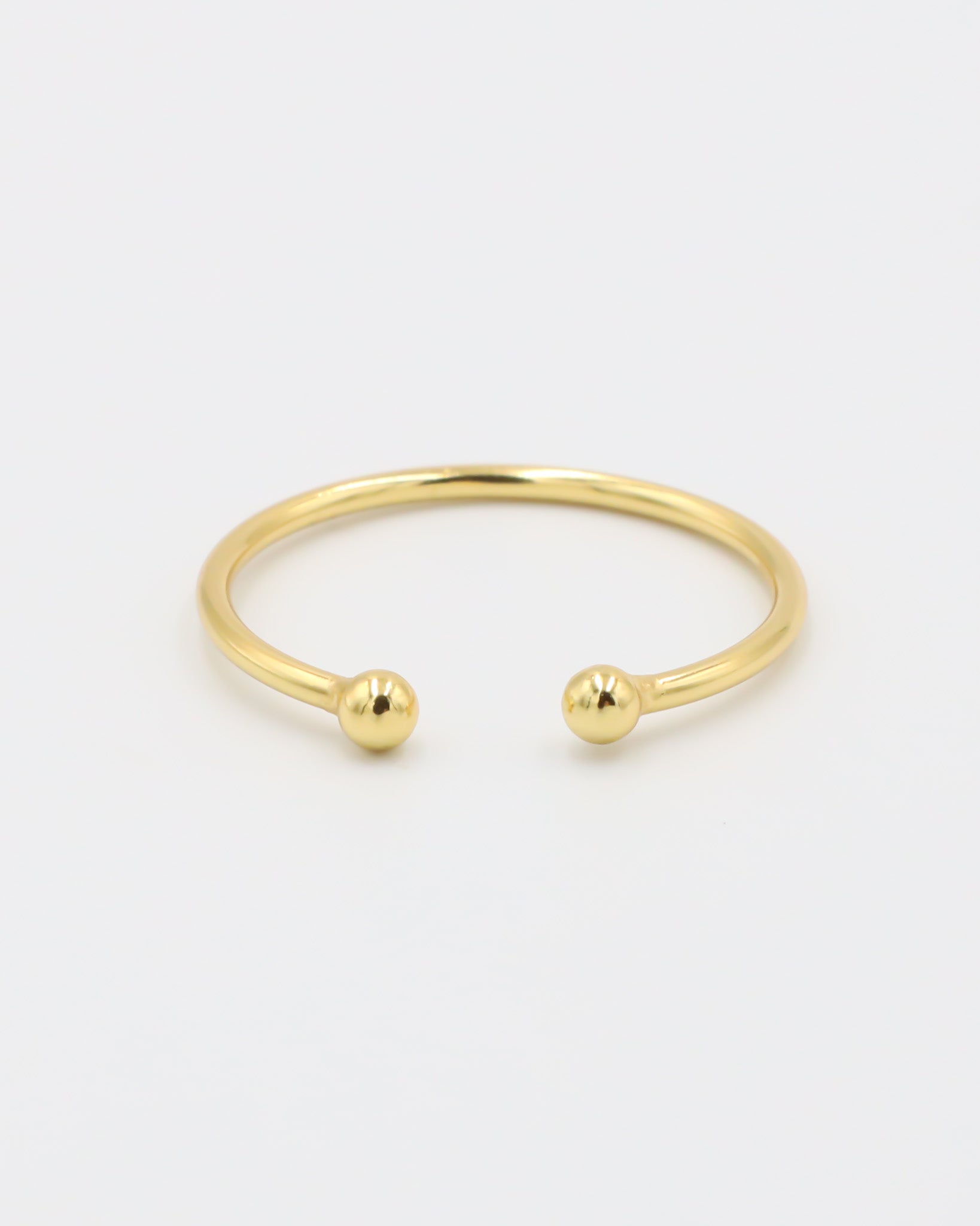 A simple gold-colored ring with two spherical decorations, displayed against a white background.